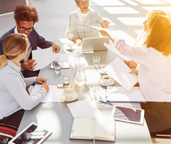 Group of people working around a shared desk, one woman is in a wheelchair