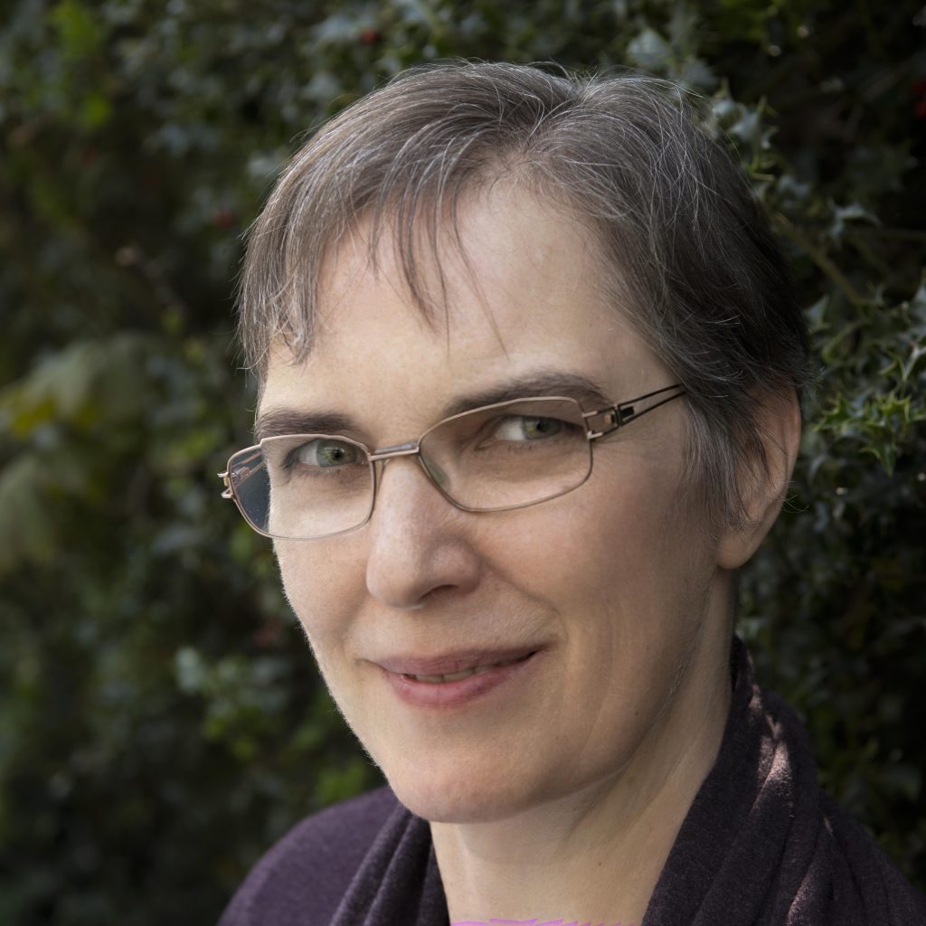 A headshot of Dr Helen Kara who is smiling and waring glasses.